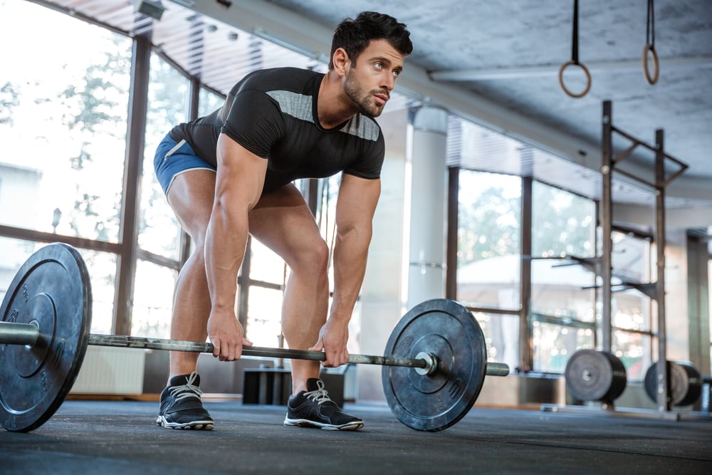Athlete wearing blue shorts and black t-shirt lifting big barbell-1