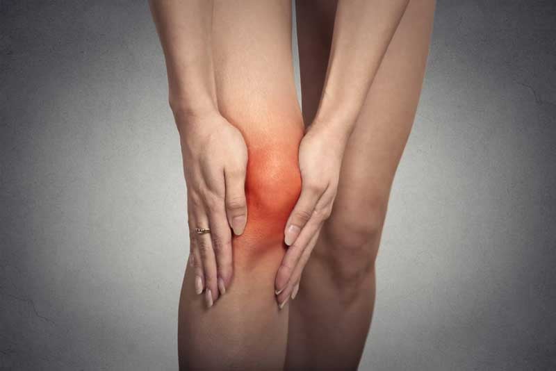 Closeup-tendon-knee-joint-problems-on-woman-leg-indicated-with-red-spot-isolated-on-gray-background.-Joint-inflammation-concept