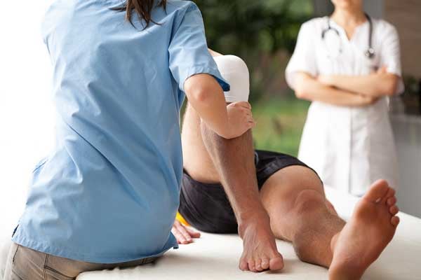 Female-physiotherapist-helping-to-exercise-the-patient-injured-knee-2