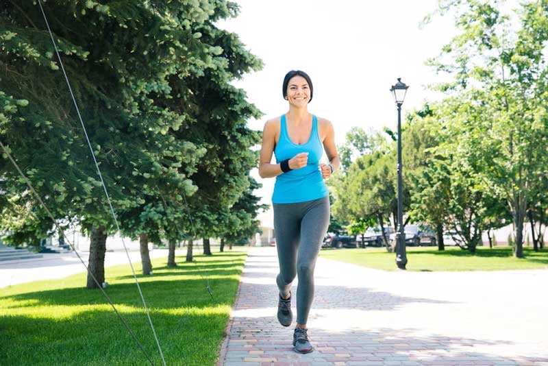 Full-length-portrait-of-a-happy-sports-woman-running-outdoors