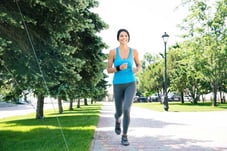 Smiling sporty woman running outdoors in park