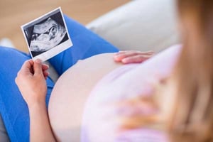 Pregnant person touching their belly looking at ultrasound