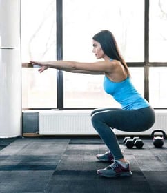 Side view portrait of a young woman doing squats with a painfree piriformis