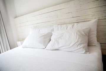 White bedroom with a king size bed and pillows.-1